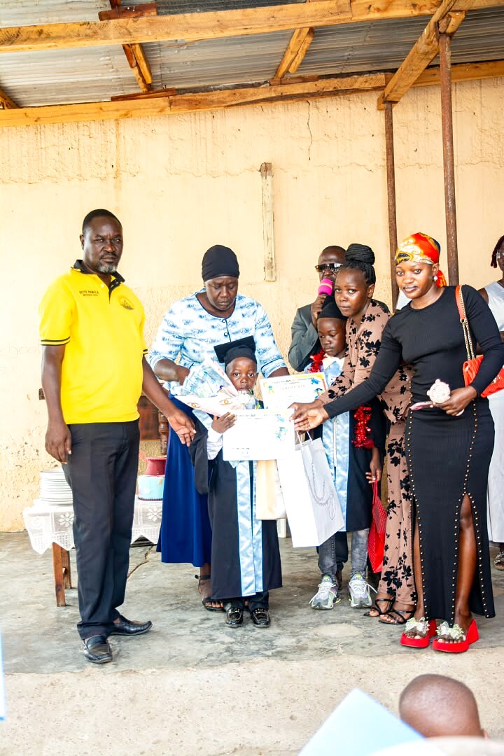 A child holds a certificate with family members at a ceremony.